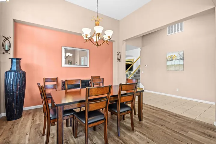 Formal dining area featuring vaulted ceilings, wood-finish flooring, and a dedicated accent wall