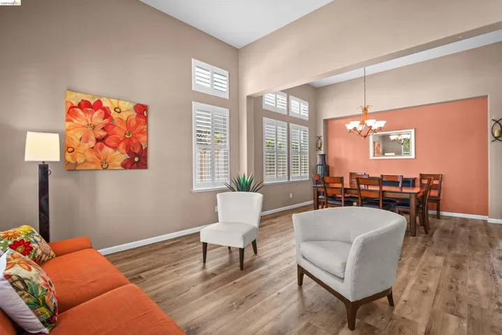 Open-concept living area featuring wood-finish flooring, high ceilings, and white plantation shutters