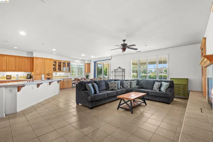 Open concept living area featuring a spacious kitchen with wood cabinetry, a large island with counter seating, and a living room with tile flooring