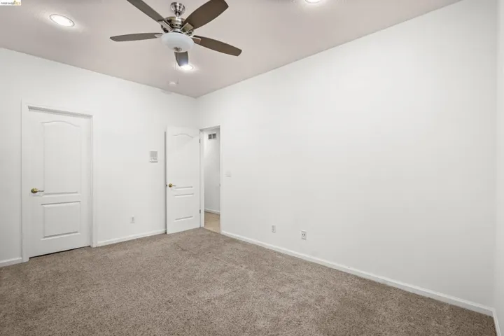 Carpeted interior space featuring white walls and a ceiling fan with integrated lighting