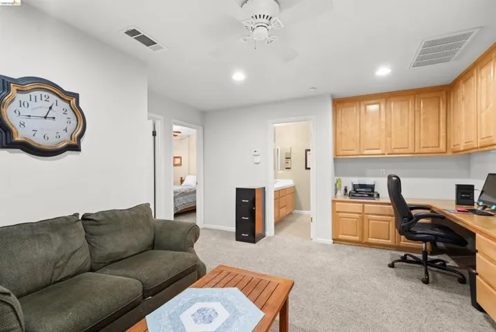 Dedicated office area featuring extensive built-in wooden cabinetry and a spacious L-shaped desk
