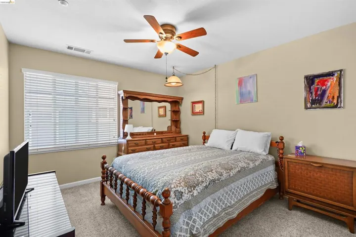 Carpeted room featuring a ceiling fan with integrated lighting, a window with horizontal blinds, and neutral-toned walls