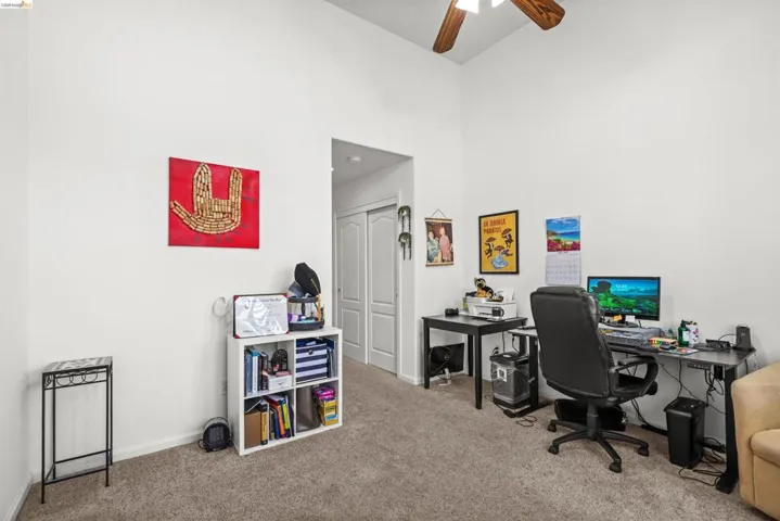 Carpeted interior space featuring vaulted ceilings and a ceiling fan with wood-finish blades