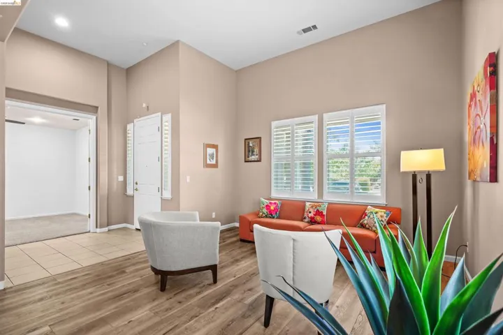 Expansive living area featuring vaulted ceilings, wood-finish flooring, and white plantation shutters on multiple windows
