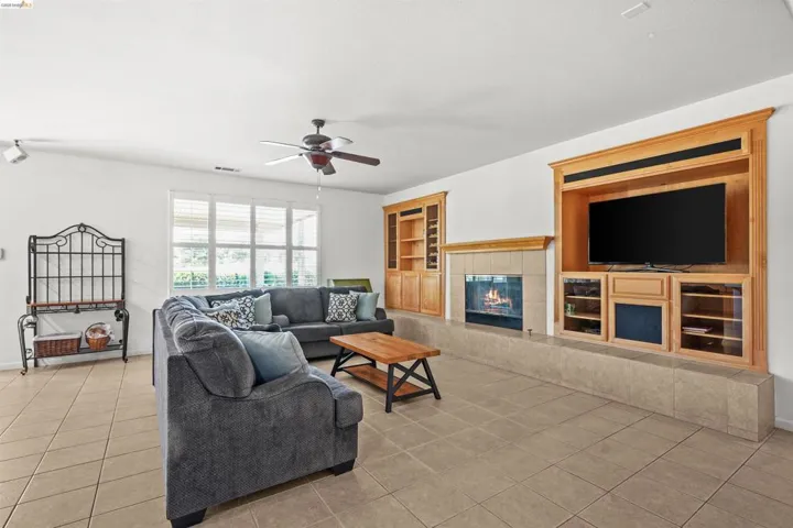 Spacious living area featuring a custom built-in entertainment center, a gas fireplace with a tile surround, and light tile flooring