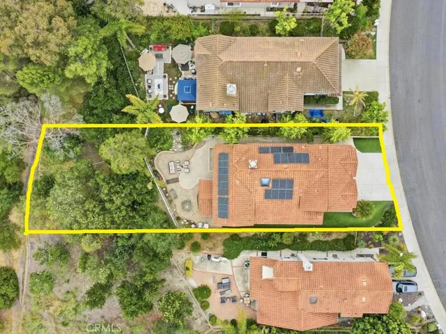 Airial view of lot including wooded slope behind patio