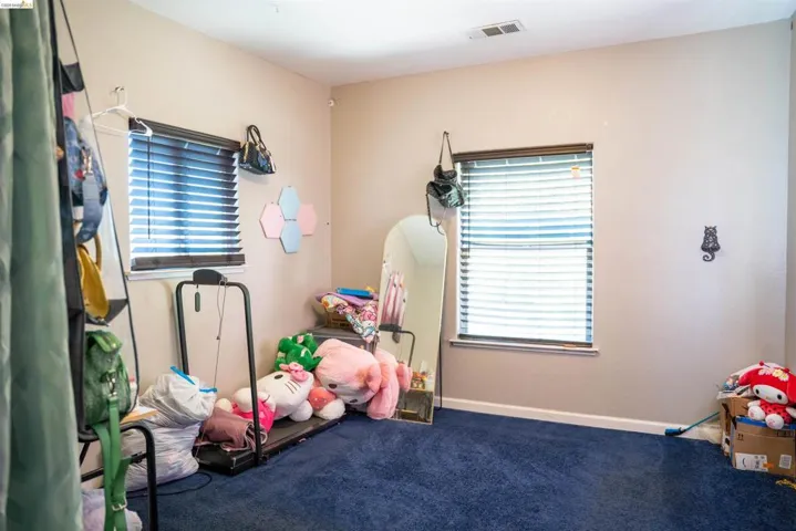 Room featuring two windows with horizontal blinds, light-colored walls, and blue carpeting