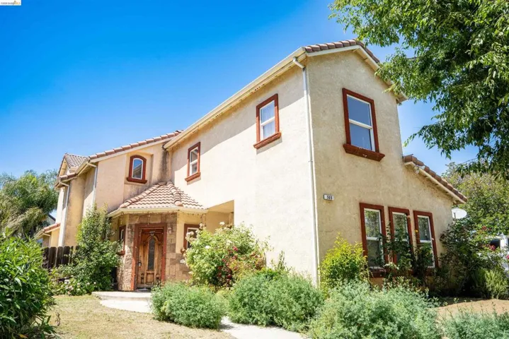 Stucco exterior residence featuring a terracotta tile roof and decorative stone accents around the main entry
