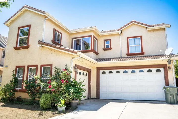 Stucco exterior with a tile roof, featuring multiple windows with contrasting trim