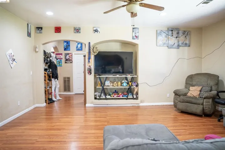 Spacious interior featuring wood-finish flooring, light-colored walls, and a ceiling fan with integrated lighting