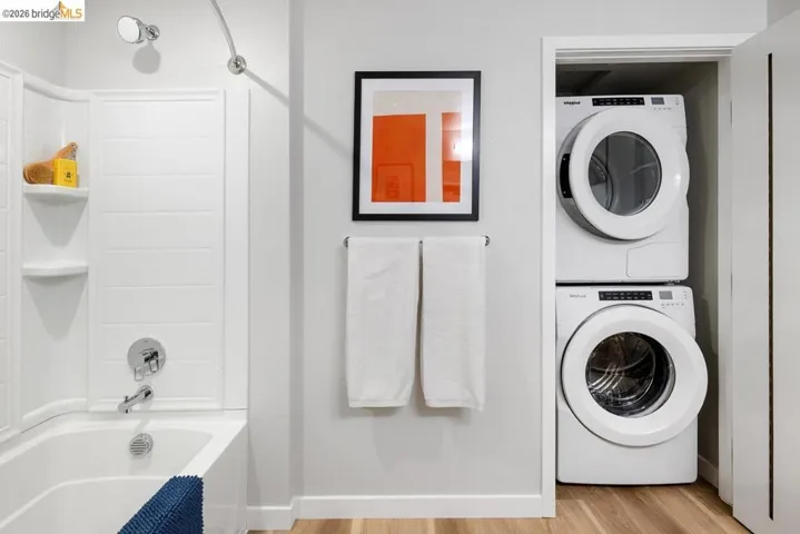 Bathroom featuring a white tub with integrated shelving, chrome fixtures, and a white shower surround