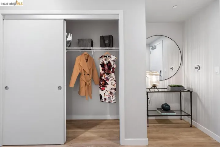 Entryway featuring wood-finish flooring, a full-length closet with sliding doors, and a round wall-mounted mirror
