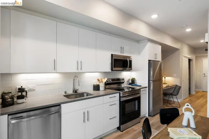 Modern kitchen featuring white flat-panel cabinetry, stainless steel appliances, a subway tile backsplash, and composite countertops