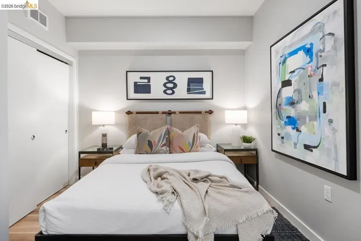 Bedroom featuring light wood-finish flooring, white walls, and a built-in closet with sliding doors