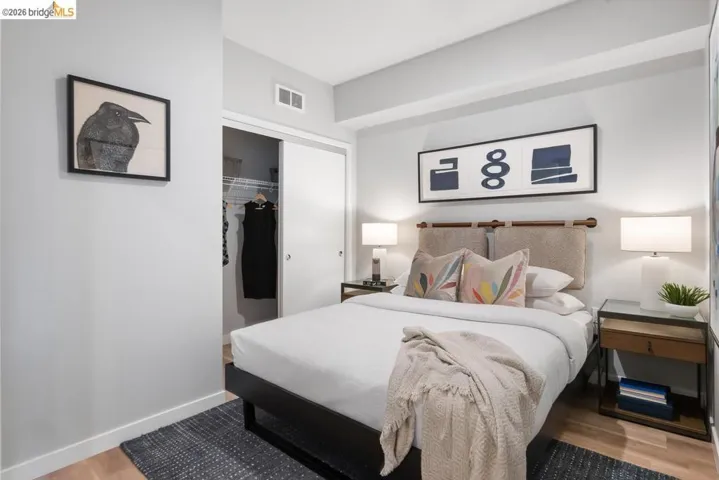Bedroom featuring wood-finish flooring, light grey wall paint, and a built-in closet with sliding doors