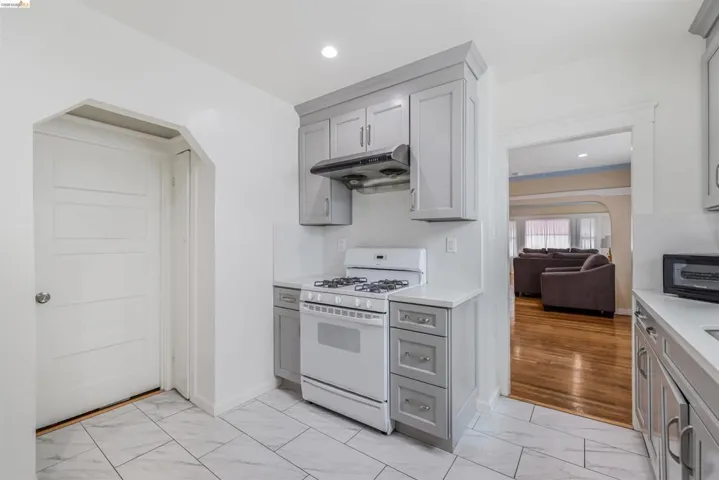 Kitchen featuring arched walkways, gray cabinets, gas range gas stove, light marble finish flooring, and recessed lighting
