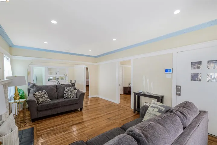 Living area featuring wood finished floors, recessed lighting, arched walkways, and crown molding