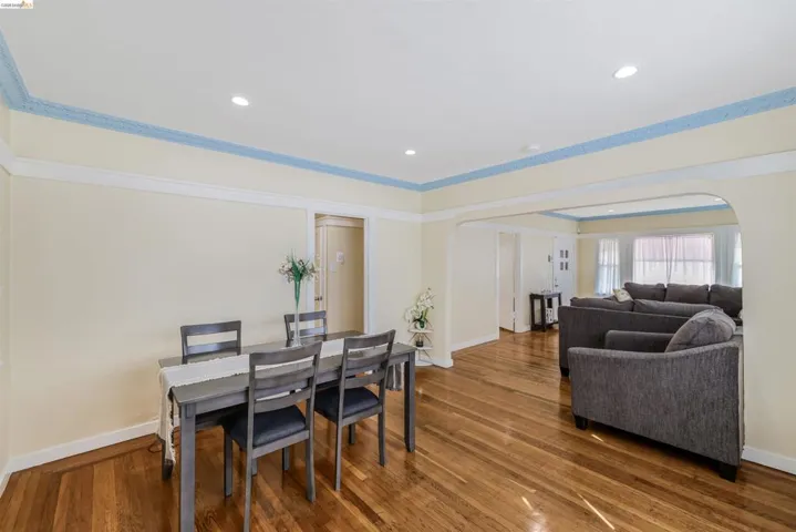 Dining space with arched walkways, dark wood-type flooring, recessed lighting, a raised ceiling, and ornamental molding