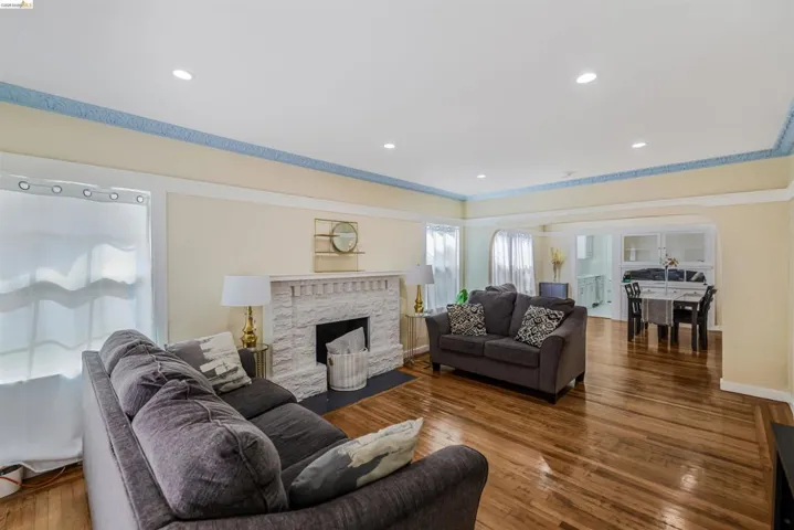 Living area with wood-type flooring, recessed lighting, crown molding, a fireplace, and arched walkways