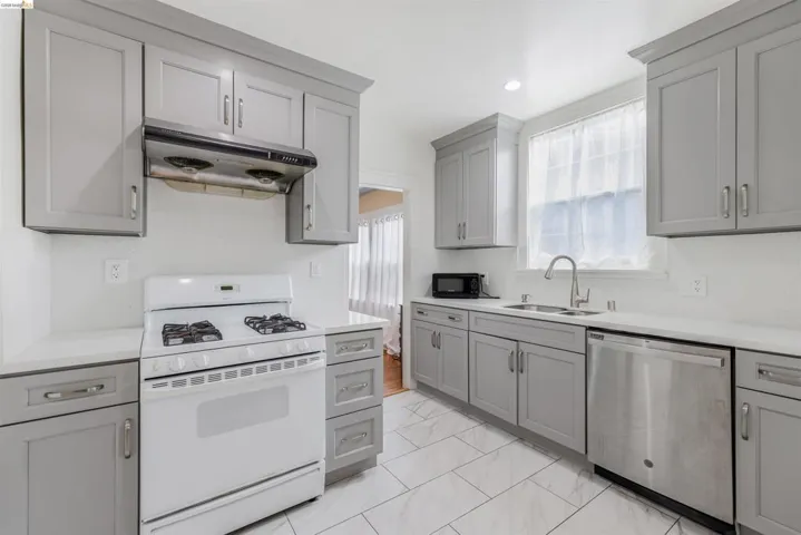 Kitchen with gray cabinetry, white gas stove, dishwasher, under cabinet range hood, and recessed lighting