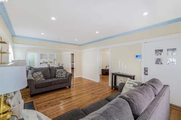 Living area featuring wood finished floors, arched walkways, recessed lighting, and ornamental molding