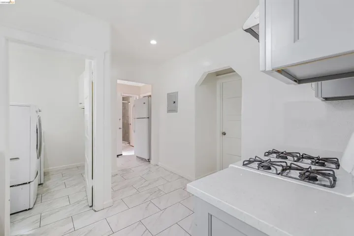 Kitchen with white appliances, light marble finish floors, light stone countertops, recessed lighting, and arched walkways
