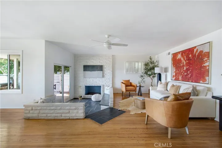 View of living room, fireplace sitting area and slider into back side covered patio.