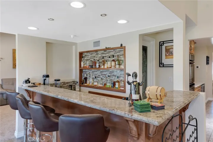 Wet Bar With Granite Counter And Custom Glass Tiled Display Shelving