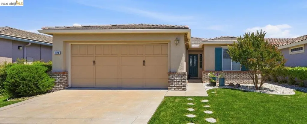 Front exterior with a two-car garage, concrete driveway, and a front walkway featuring circular stepping stones