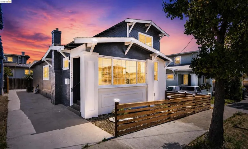 Craftsman-style home featuring a dark exterior, white trim, prominent front windows, and a side driveway