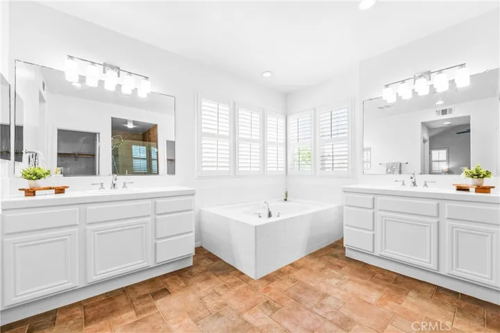 The expansive primary suite offers soaring ceilings, dramatic wall-to-wall windows, a unique upper loft retreat, spa-inspired bath with soaking tub, dual vanities, a linen closet, and a walk-in closet.