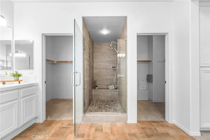 The expansive primary suite offers soaring ceilings, dramatic wall-to-wall windows, a unique upper loft retreat, spa-inspired bath with soaking tub, dual vanities, a linen closet, and a walk-in closet.