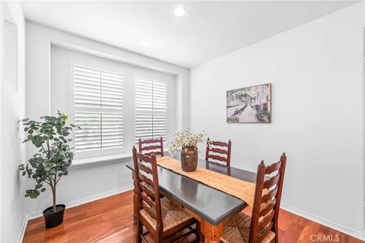 Warm and inviting formal dining room with hardwood flooring, with oversized picture window overlooking the backyard and elegant architectural pass through openings that create an airy connection to the adjacent living spaces.