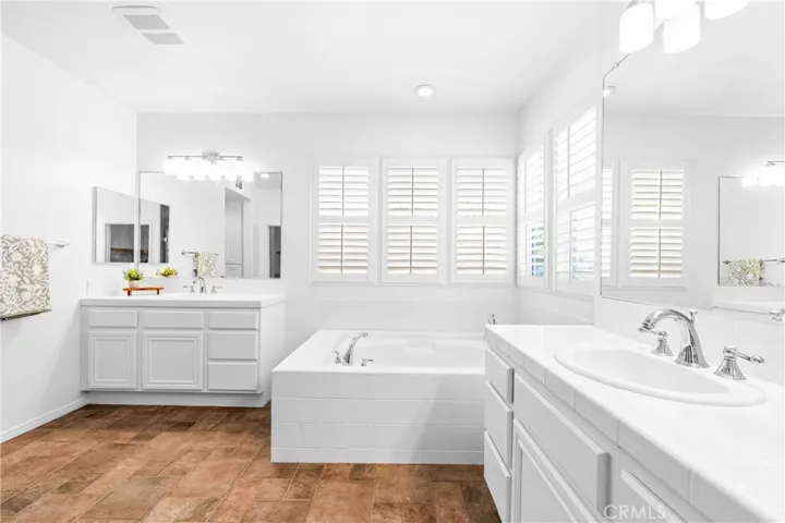 The expansive primary suite offers soaring ceilings, dramatic wall-to-wall windows, a unique upper loft retreat, spa-inspired bath with soaking tub, dual vanities, a linen closet, and a walk-in closet.