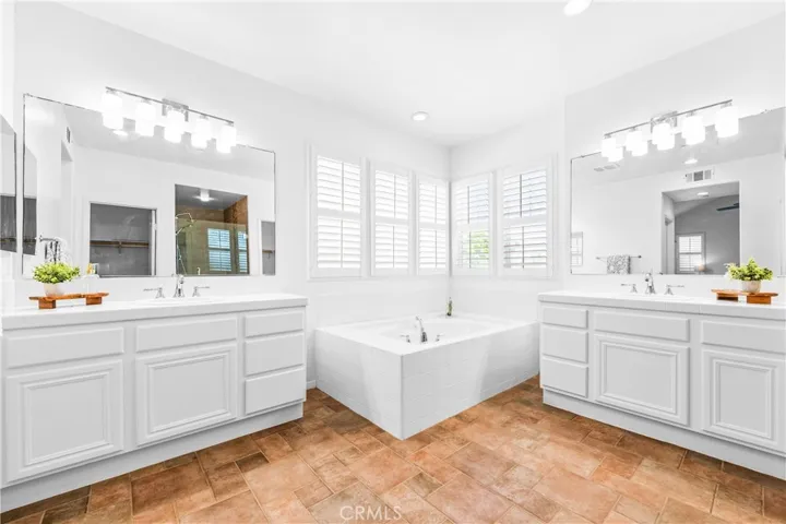 The expansive primary suite offers soaring ceilings, dramatic wall-to-wall windows, a unique upper loft retreat, spa-inspired bath with soaking tub, dual vanities, a linen closet, and a walk-in closet.