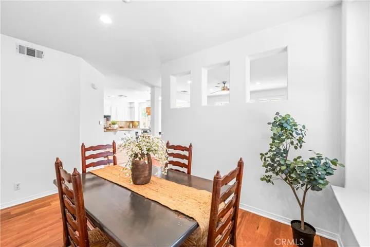 Warm and inviting formal dining room with hardwood flooring, with oversized picture window overlooking the backyard and elegant architectural pass through openings that create an airy connection to the adjacent living spaces.