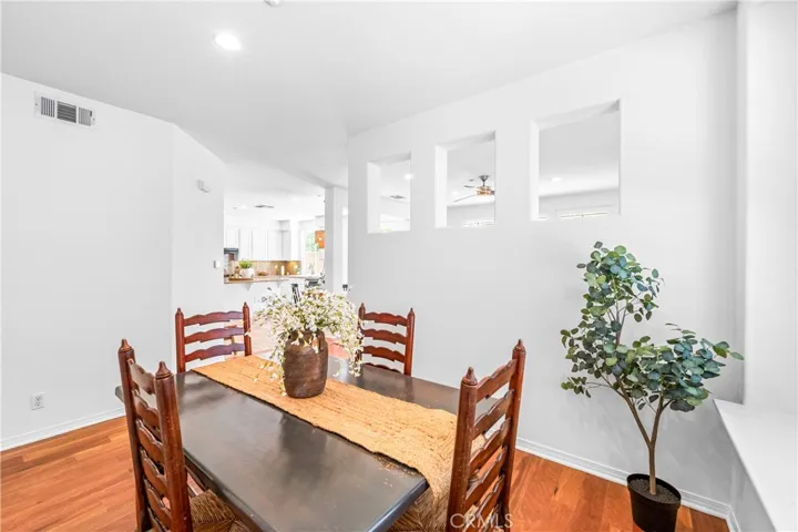 Warm and inviting formal dining room with hardwood flooring, with oversized picture window overlooking the backyard and elegant architectural pass through openings that create an airy connection to the adjacent living spaces.