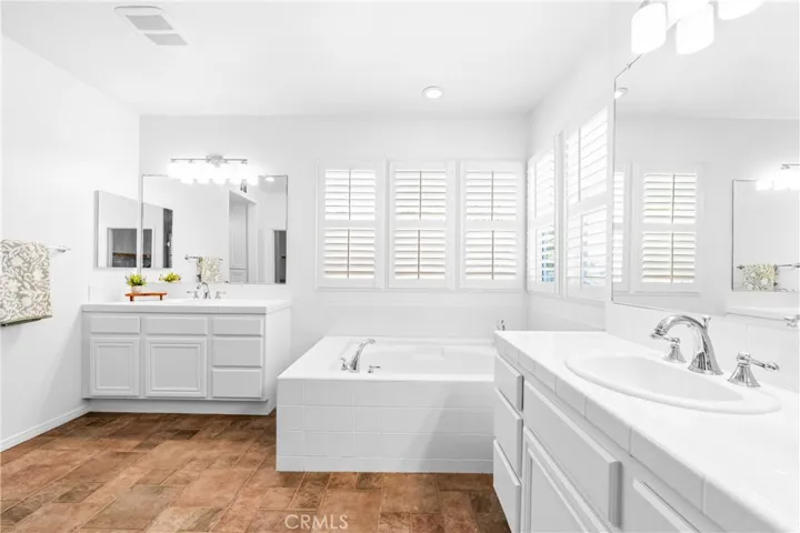 The expansive primary suite offers soaring ceilings, dramatic wall-to-wall windows, a unique upper loft retreat, spa-inspired bath with soaking tub, dual vanities, a linen closet, and a walk-in closet.