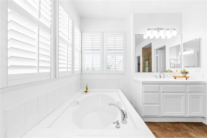 The expansive primary suite offers soaring ceilings, dramatic wall-to-wall windows, a unique upper loft retreat, spa-inspired bath with soaking tub, dual vanities, a linen closet, and a walk-in closet.