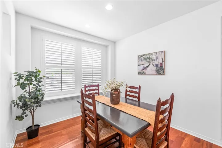 Warm and inviting formal dining room with hardwood flooring, with oversized picture window overlooking the backyard and elegant architectural pass through openings that create an airy connection to the adjacent living spaces.
