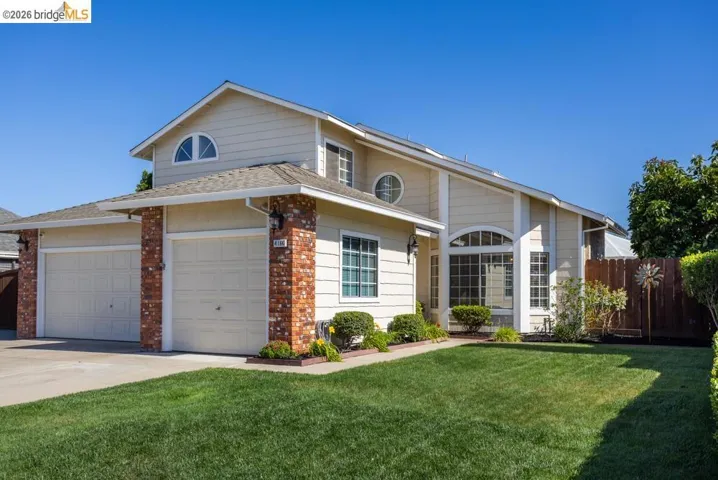 Two-story residence featuring a front lawn and brick veneer accents
