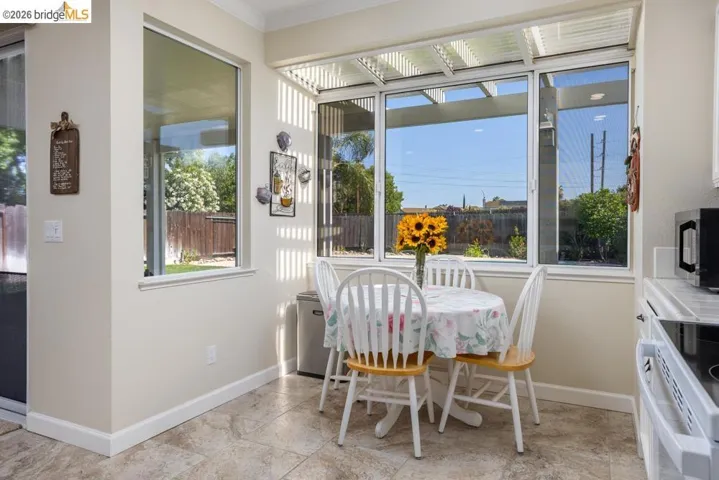 Breakfast nook featuring tile flooring, crown molding, and multiple windows with outdoor access