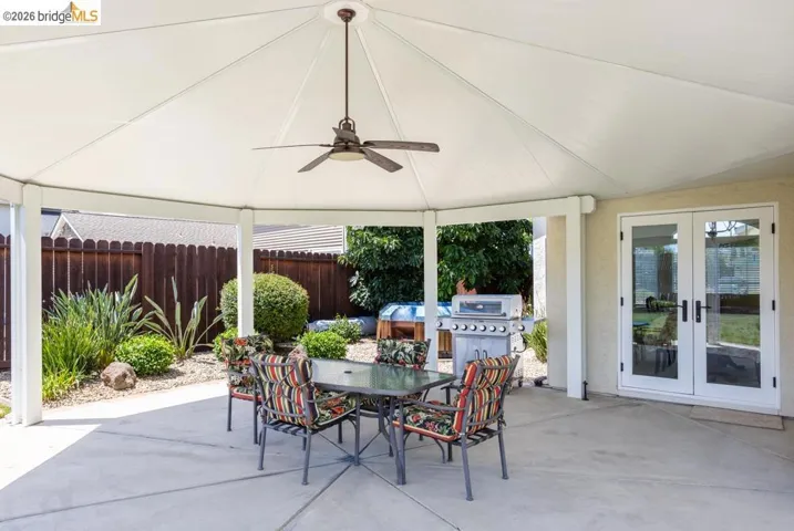 Spacious covered patio featuring a ceiling fan, concrete flooring, and direct access to the interior via double French doors