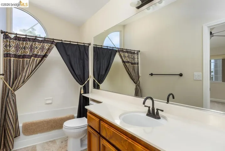Bathroom featuring an arched transom window, a single vanity with a white countertop, a drop-in sink, and a dark bronze faucet