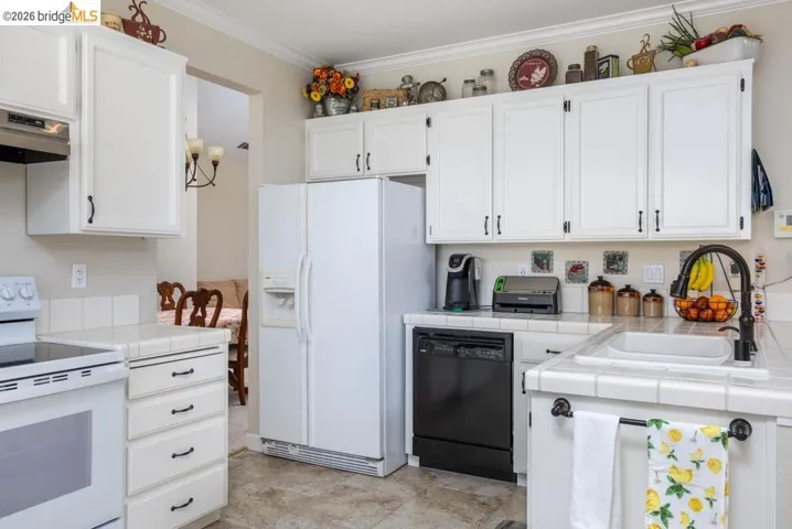 Kitchen featuring white cabinetry with black hardware, tile countertops, a white electric range, and a black dishwasher