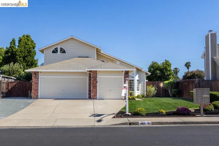 Two-story residence featuring a dual garage, brick accents, and a front lawn with established landscaping