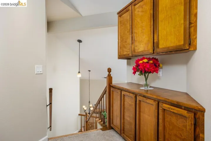 Built-in wood cabinetry with storage, wood-finish staircase with balusters, and pendant lighting fixtures