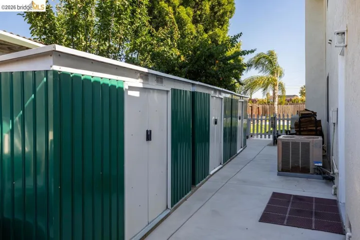 Row of metal storage sheds with green and white panels