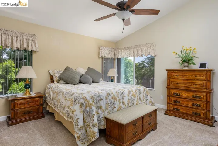 Carpeted room featuring a vaulted ceiling and a ceiling fan with light fixture