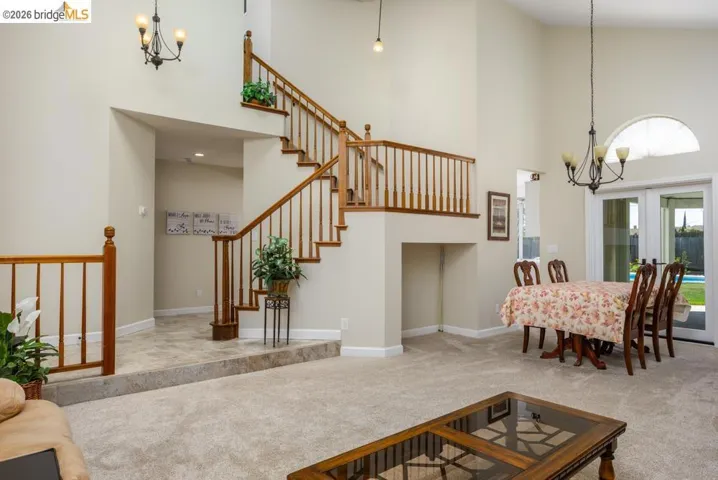 Two-story foyer featuring a grand staircase with wood railings, vaulted ceilings, and a tile-floored entry